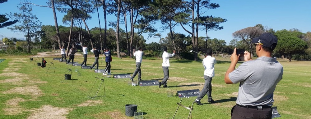 Hillwood students practising their swings at the driving range with a coach
